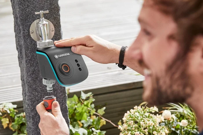 Person montiert einen Bewässerungscomputer an einen Wasserhahn.